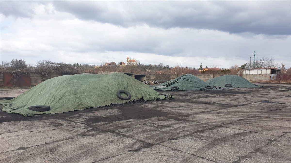 Hromady uhlí zakryté plachtami na skladové ploše v Sadské